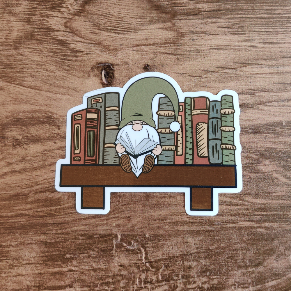 A gnome sitting on a bookshelf with books on either side of him.