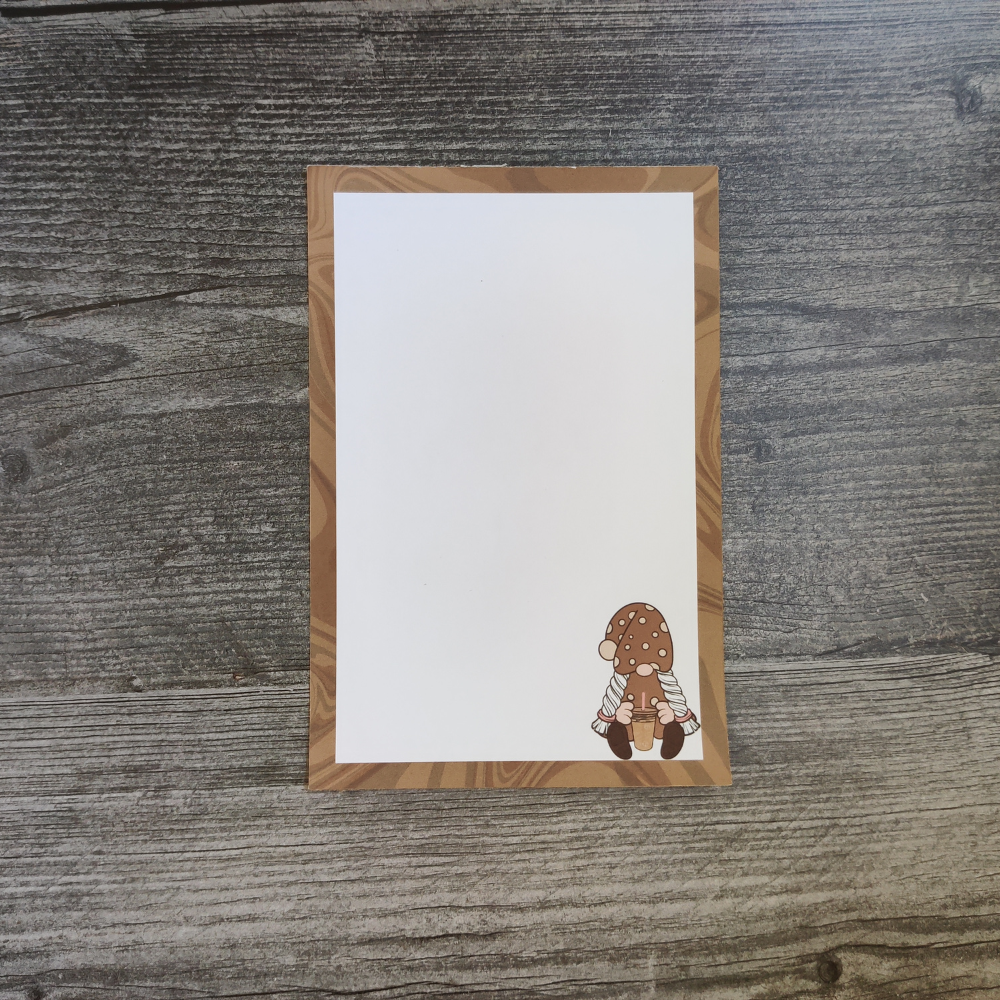 A brown and white notepad with a girl gnome in the bottom right corner. She is wearing a brown polka-dot dress and is holding an iced coffee.