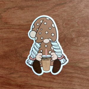 A girl gnome in a brown and cream polka dot dress and hat. She is holding an iced coffee sticker.
