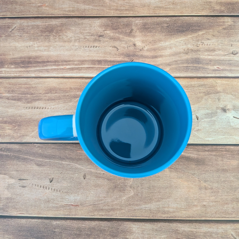 A top-down view of a white ceramic mug. The inside of the mug is blue, and the handle is blue.