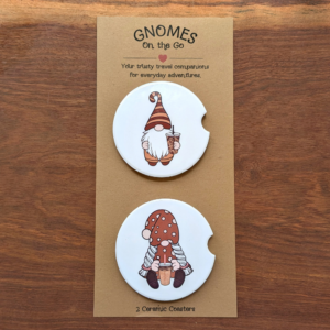 A set of 2 iced coffee gnome white ceramic car coasters. The top coaster features a gnome in a brown striped hat. The bottom coaster features a girl gnome in a polka-dot dress.