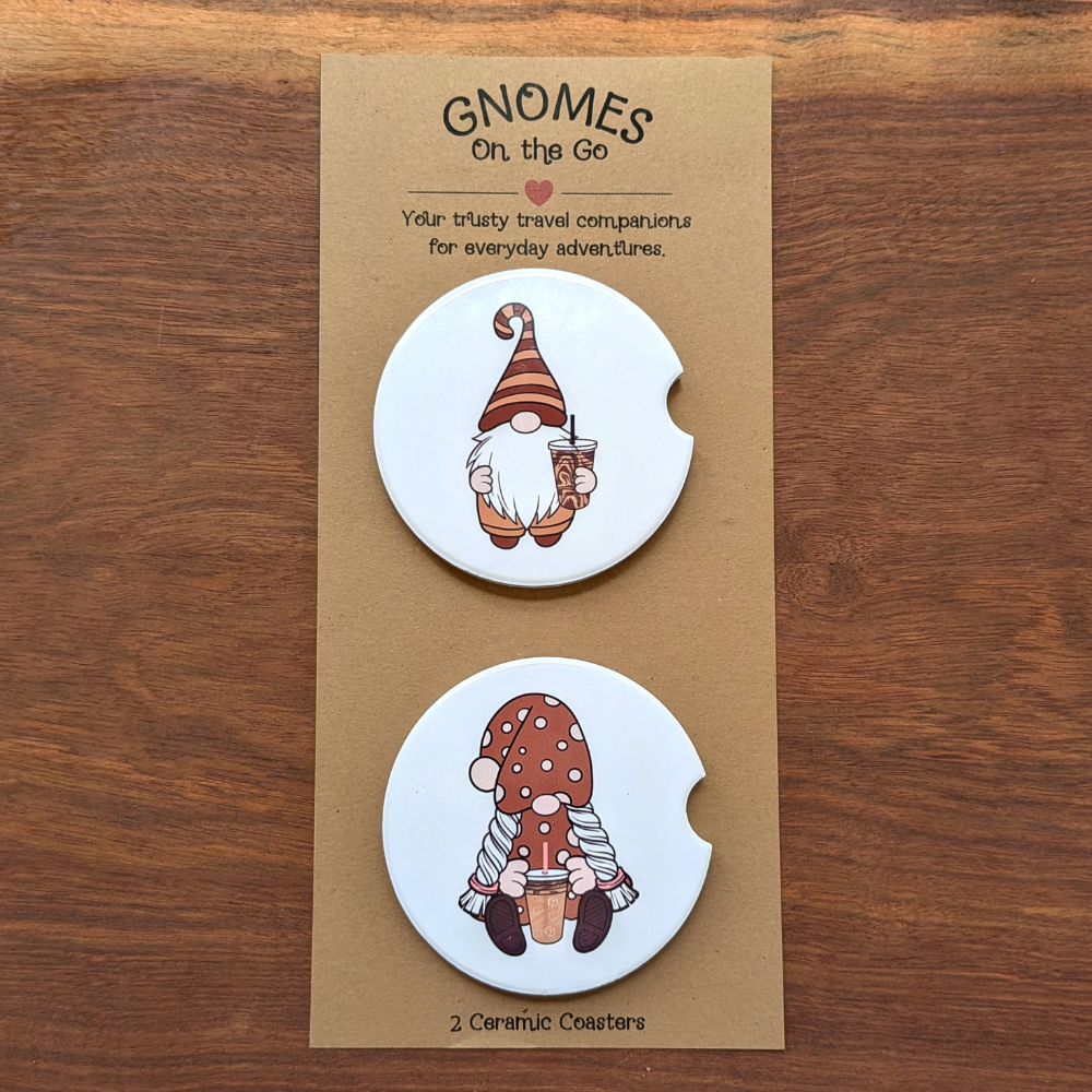 A set of 2 iced coffee gnome white ceramic car coasters. The top coaster features a gnome in a brown striped hat. The bottom coaster features a girl gnome in a polka-dot dress.