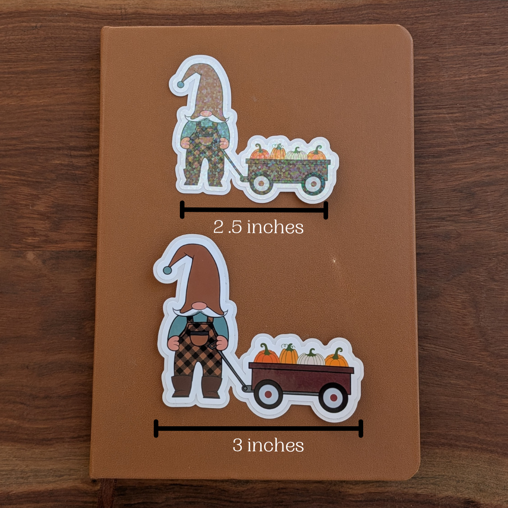 Two fall pumpkin patch gnome stickers are sitting on a brown journal. The top sticker measures 2.5 inches wide, and the bottom sticker measures 3 inches wide.