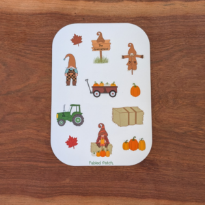A fall gnome sticker sheet featuring 2 gnomes, a tractor, a wagon full of pumpkins, and a hay bale. The sticker sheet has brown, orange, and green colors.