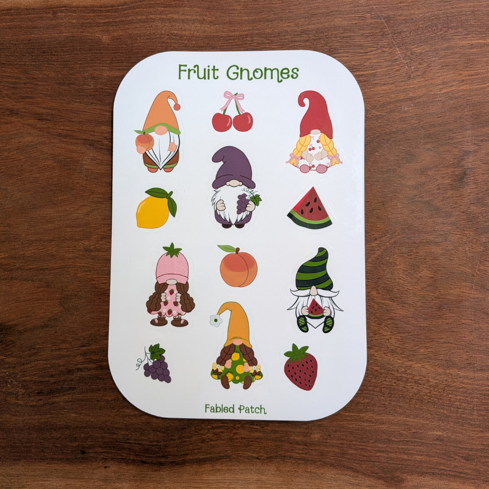A sticker sheet featuring colorful illustrations of fruit gnomes. The gnomes are depicted with various fruits, including cherries, a lemon, a watermelon, a peach, grapes, and a strawberry.