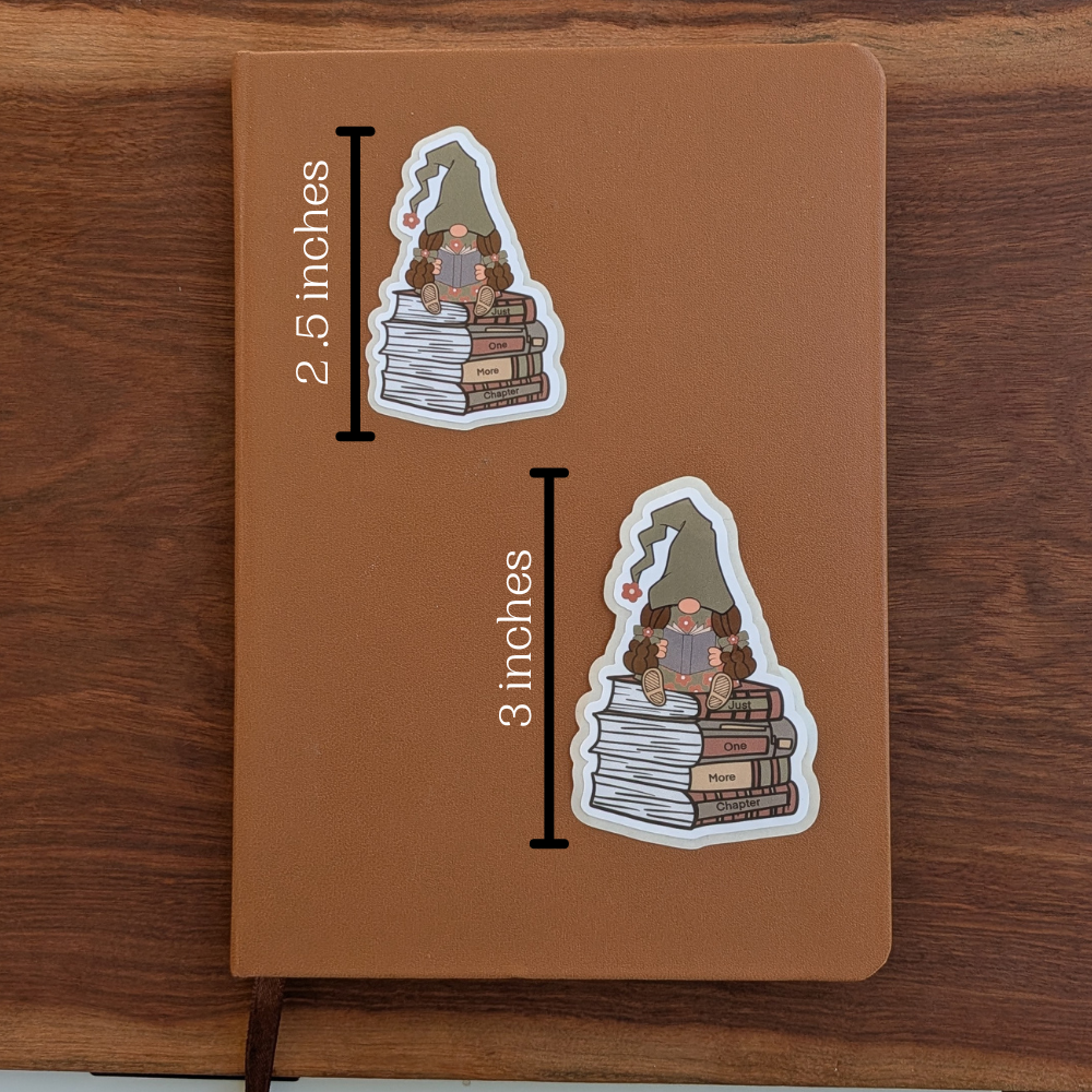 Two girls reading gnome stickers sit on a brown journal. The top sticker measures 2.5 inches tall, and the bottom sticker measures 3 inches tall.