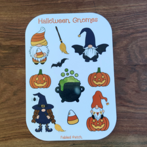 A Halloween Gnome sticker sheet. The gnomes are dressed as candy corn, a bat, a witch, and a gnome sitting on a jack-o-lantern.