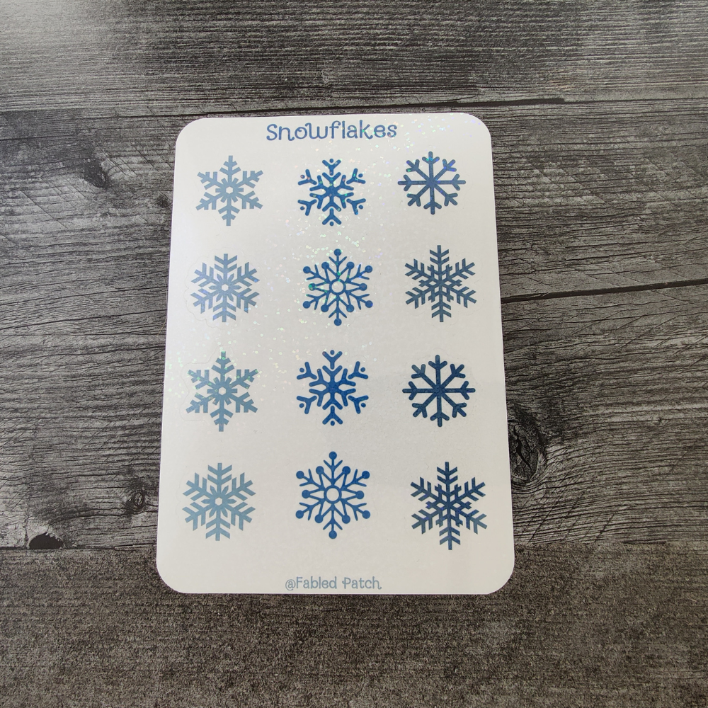 A white sticker sheet with 12 blue snowflake stickers, 6 designs in total.