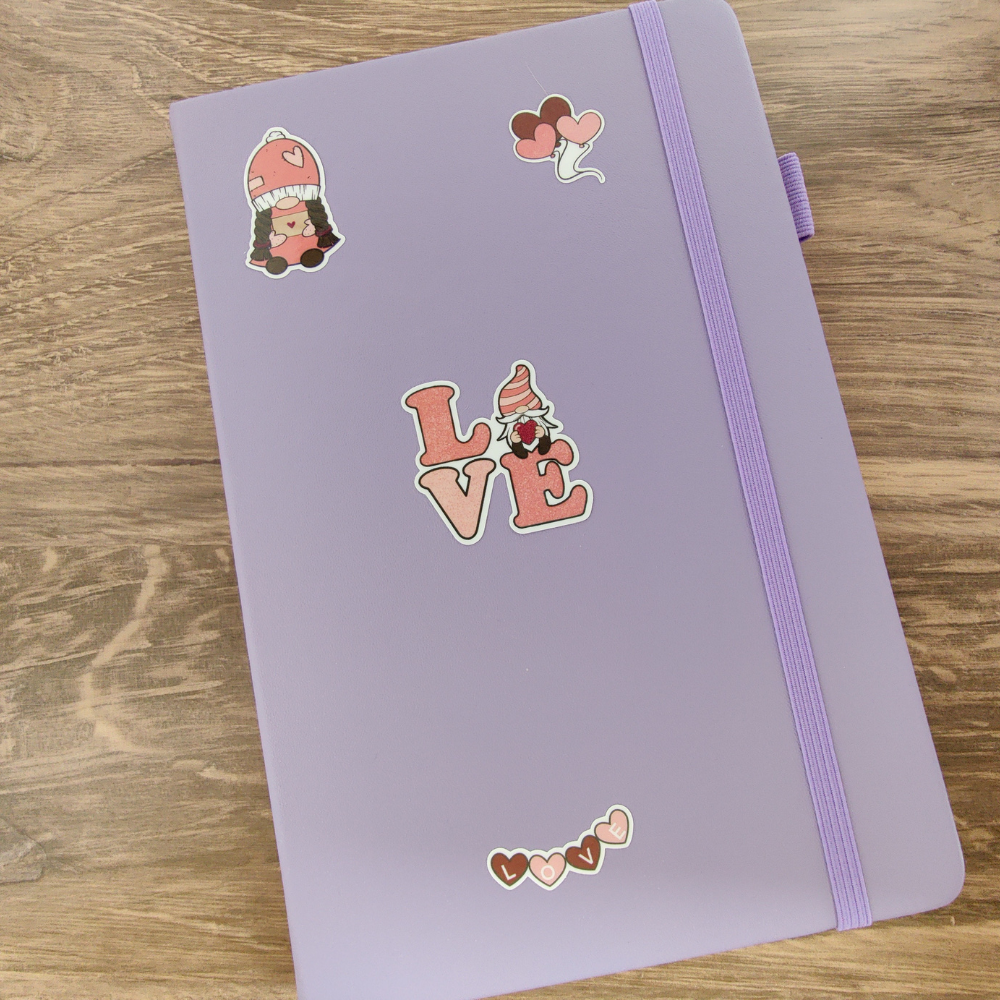 A purple journal with 4 Valentine's Day Gnome stickers. The stickers are pink and red.
