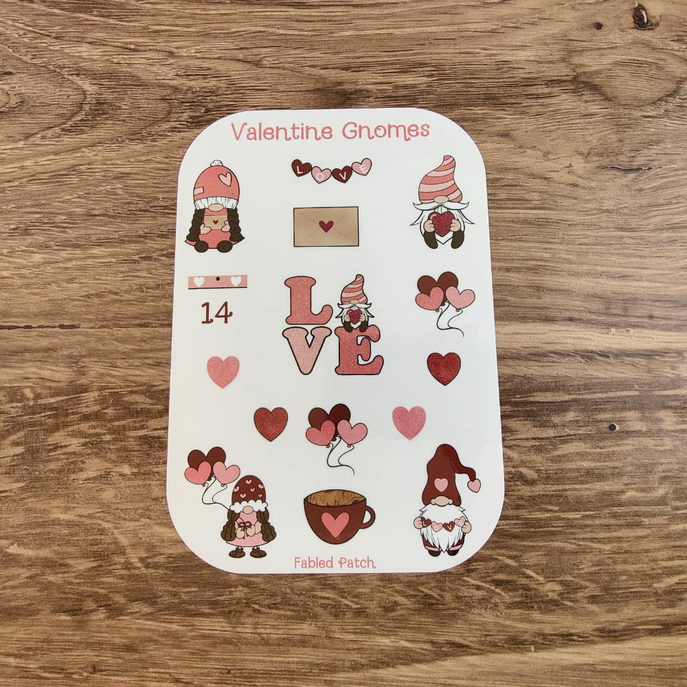 A sheet of Valentine's Day-themed stickers featuring gnomes, hearts, and the word "LOVE". The stickers are in shades of pink, red, and brown.