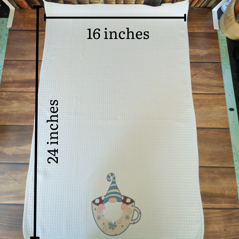 An image showing the white waffle towel measurements. The towel is 24 inches long and 16 inches wide. The winter gnome image is on the bottom.